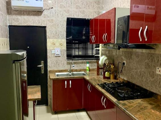 a kitchen with red cabinets and a sink at Uzzy Homes in Lagos