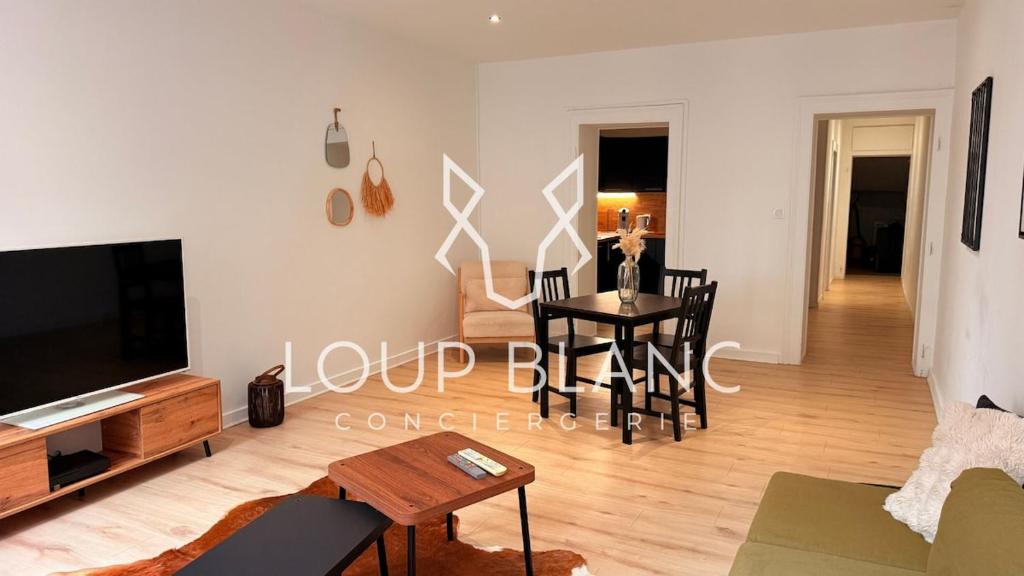 a living room with a tv and a table at Le Commerce-Gare-Centre-Ville in Montbéliard