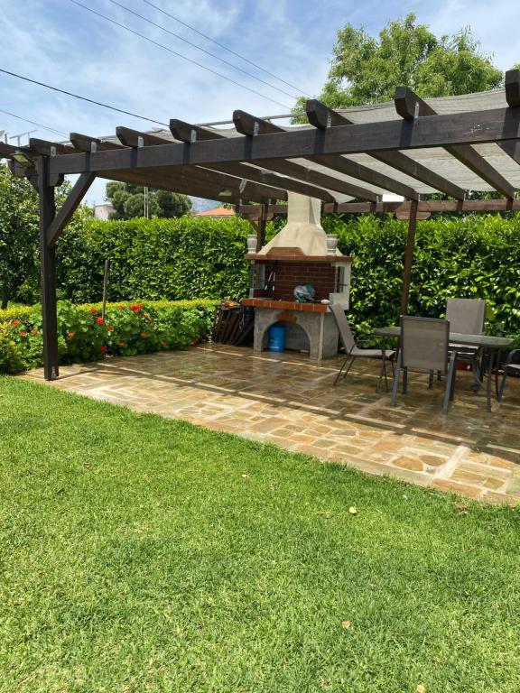 a patio with a fireplace under a wooden pergola at Family Home in Amarynthos
