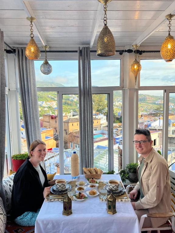 a man and woman sitting at a table with food at Dar Nomads in Chefchaouen
