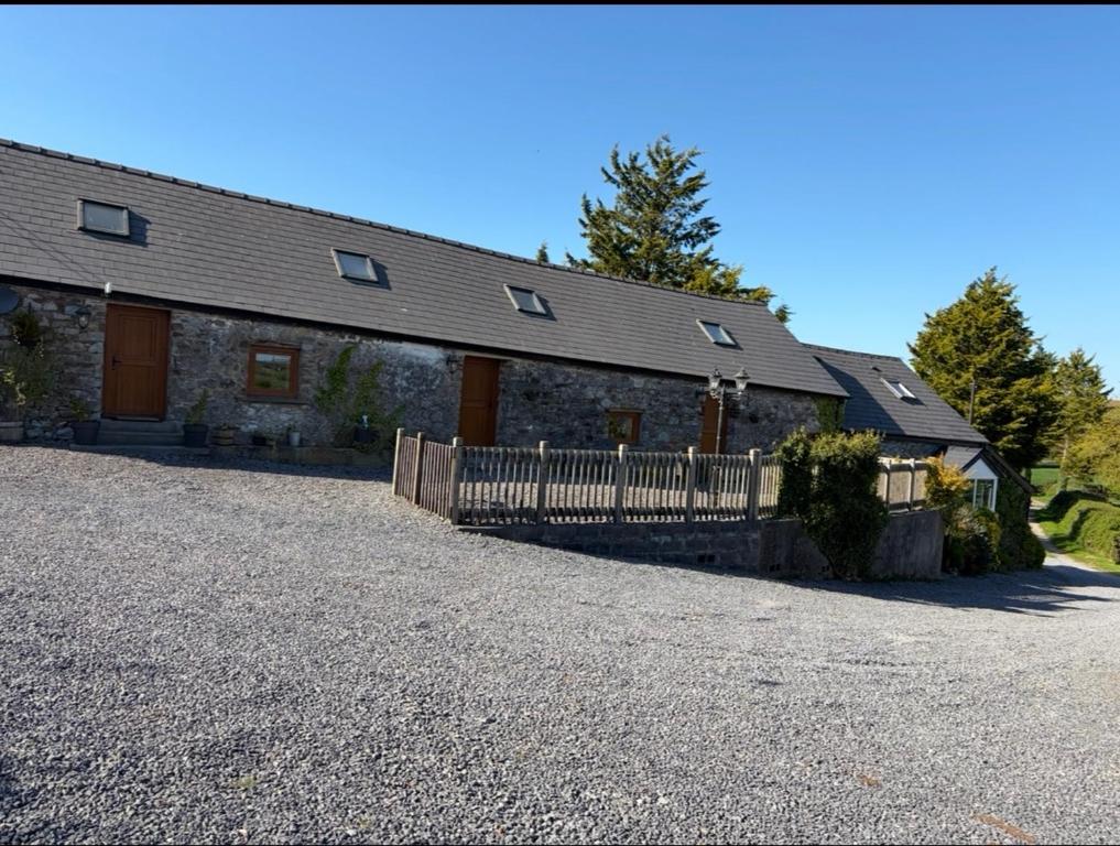a stone house with a wooden fence in front of it at Ystrad Fach Farm in Llangendeirne