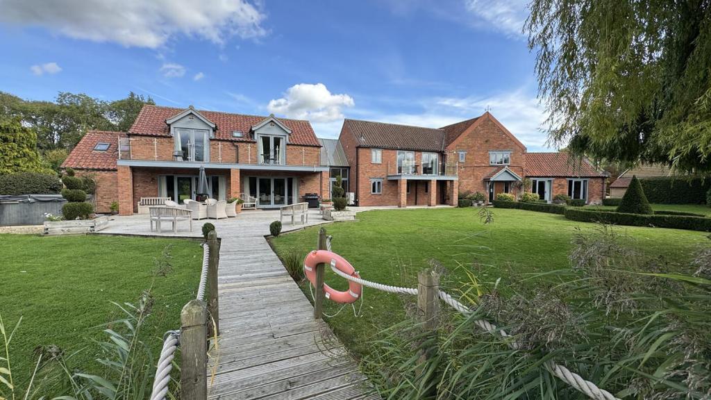 a large house with a wooden walkway in front of it at Gorse Lodge Lakeside & Courtyard in Stubton