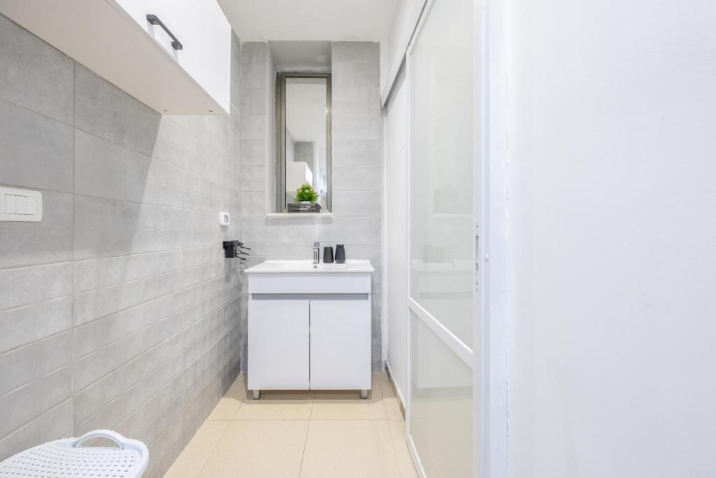 a white bathroom with a sink and a mirror at Masada34a City Center in Haifa
