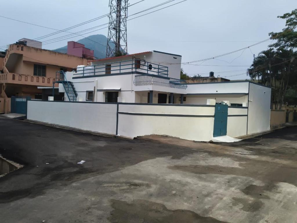 a white building with a gate in a parking lot at Urban Hostels in Tiruvannāmalai