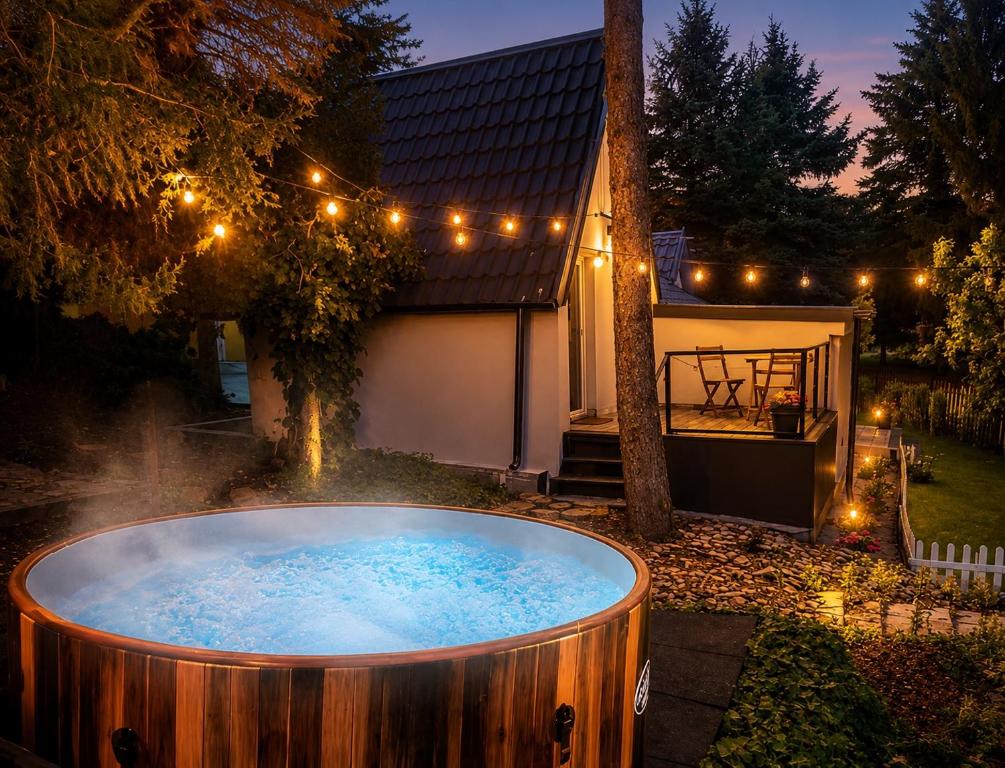 a hot tub in the yard of a house at night at Hegyi Kuckó Vendégház - Forest Hideaway with Jacuzzi in Biatorbágy