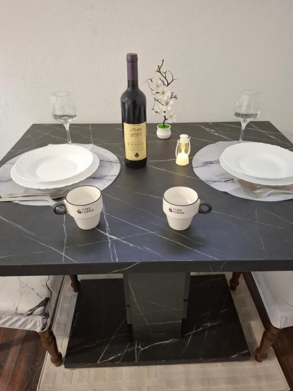 a black table with two plates and a bottle of wine at Airport apartment Delić in Golubovci