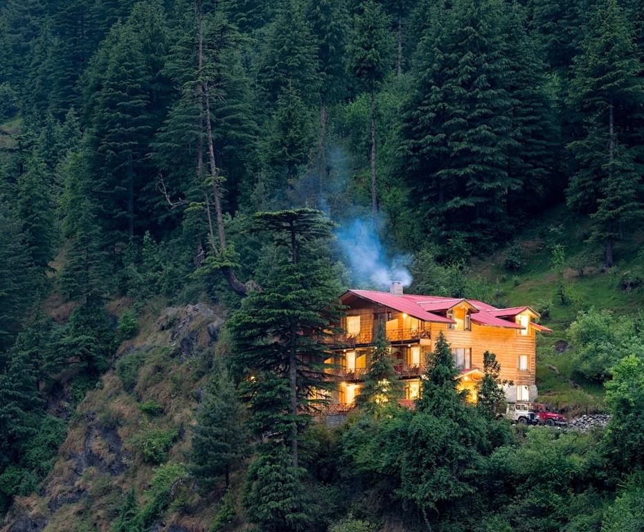 a house on the side of a hill with trees at The Pine Chalet Manali in Manāli
