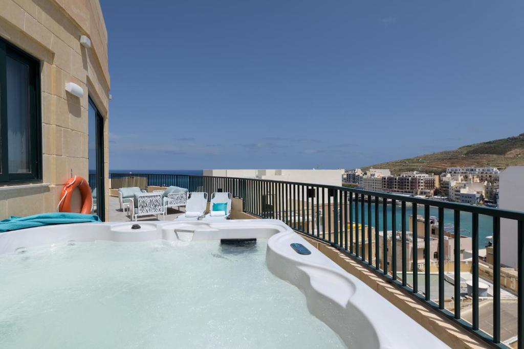 a hot tub on a balcony with a view of the ocean at Jacuzzi Penthouse with Large Terrace & Views in Marsalforn