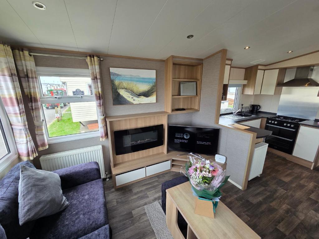 a living room with a couch and a kitchen at The Cavern Retreat in Rhyl