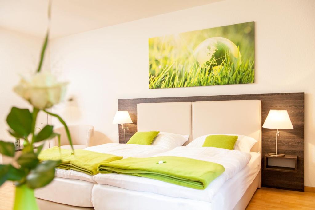 ein Schlafzimmer mit einem großen weißen Bett mit grünen Kissen in der Unterkunft Eilenriedestift Appartements in Hannover