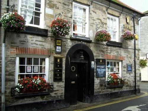 a stone building with flower boxes and a door at The Ship Inn in St Austell