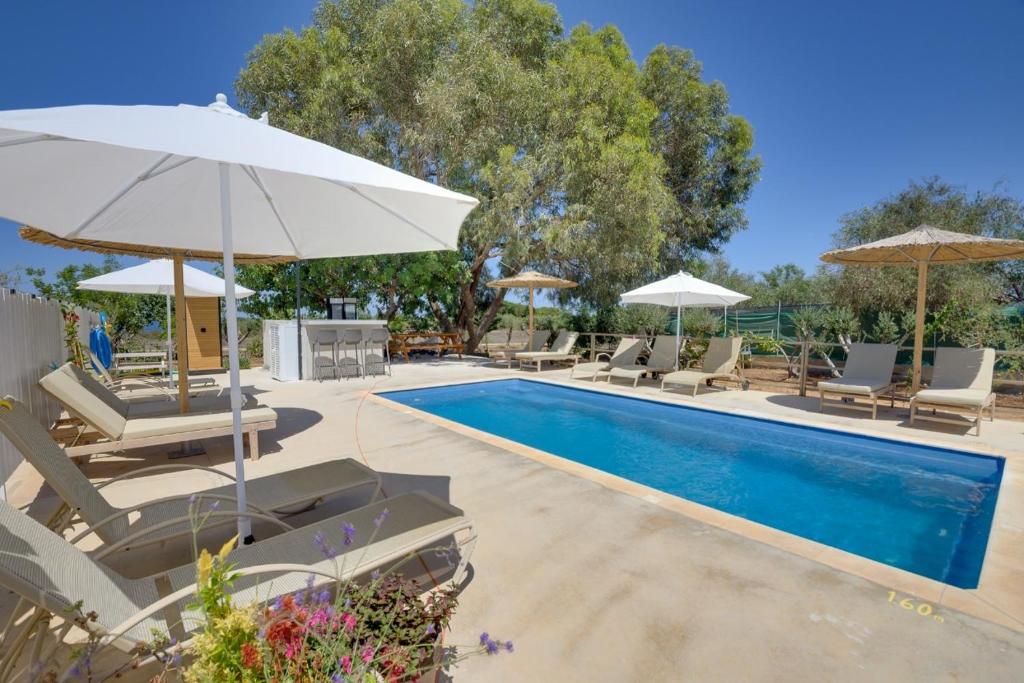 a swimming pool with chairs and umbrellas next to a pool at THE SPOT GLAMPING STUDIOS PROTARAs in Paralimni