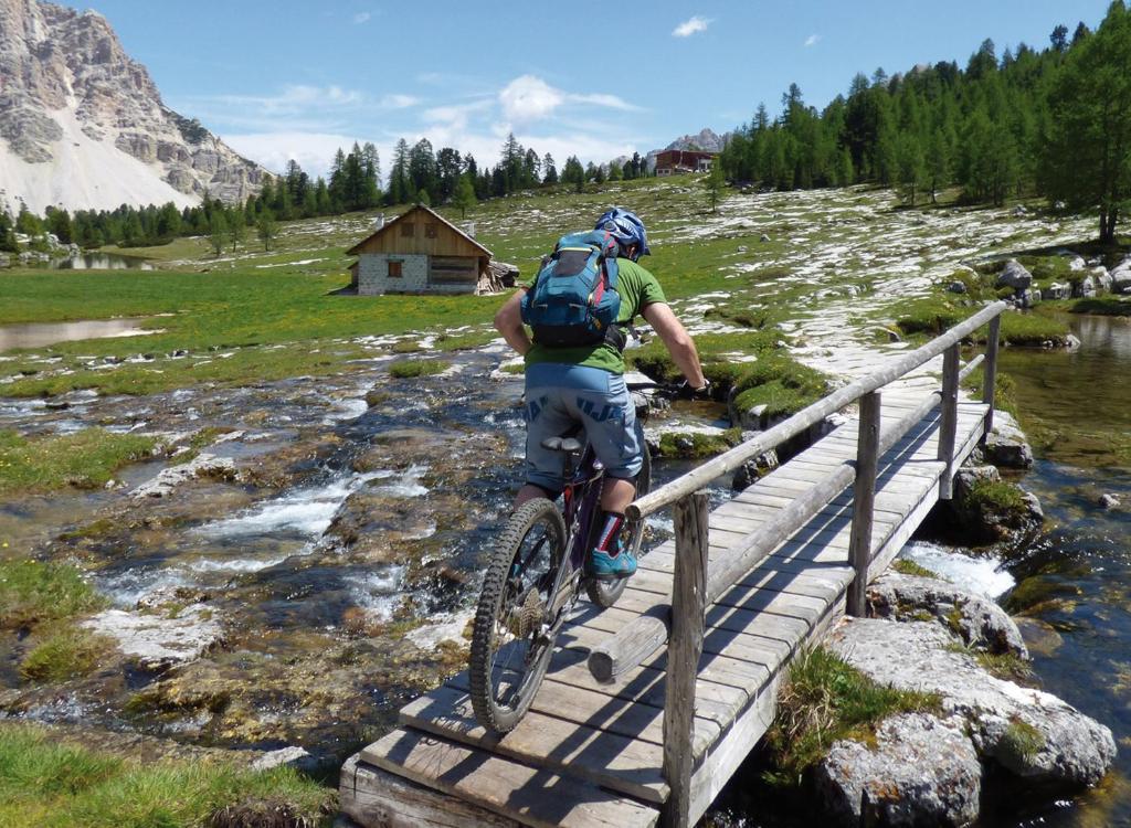 a man riding a bike next to a river at Alpinhotel Keil in Valdaora