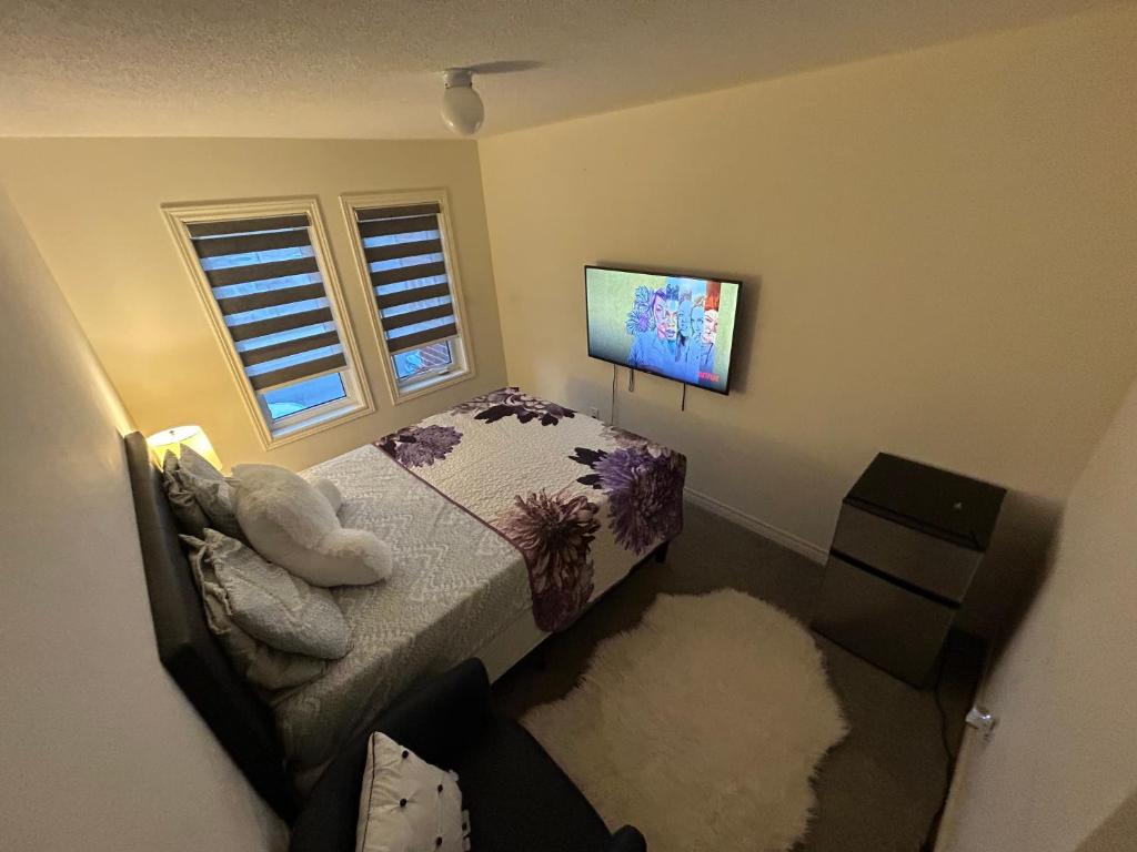 a bedroom with a bed and a flat screen tv at Relax Guest House in Oshawa