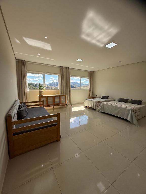 a large room with two beds and a large window at Cobertura Duplex 301 espaçoso e com vista para as montanhas in São Lourenço