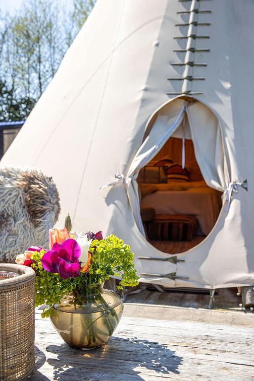 a white tent with a vase of flowers on a table at Tipi Marie at Logie Marie in Kaprijke
