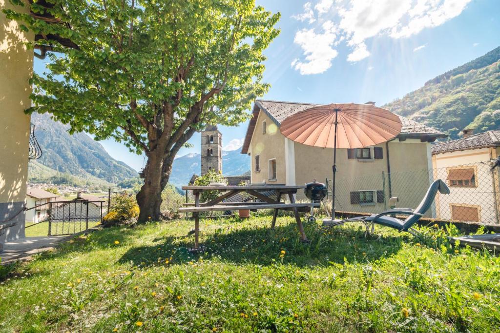 a picnic table with an umbrella next to a house at Scenic Alps View Getaway in Aquila