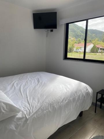 a bedroom with a white bed and a window at Refugio Callihue in El Ajial