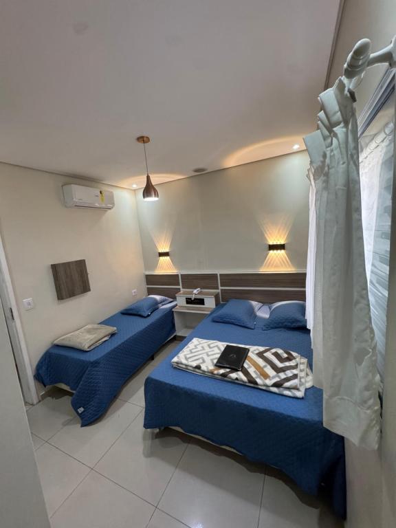 two beds in a hospital room with blue sheets at Hotel Quintino - No Coração de São Paulo, 2 Min do Metrô Sé, 10 Min do Brás, 5 Min da 25 de Março e Estacionamento no Local Grátis in São Paulo