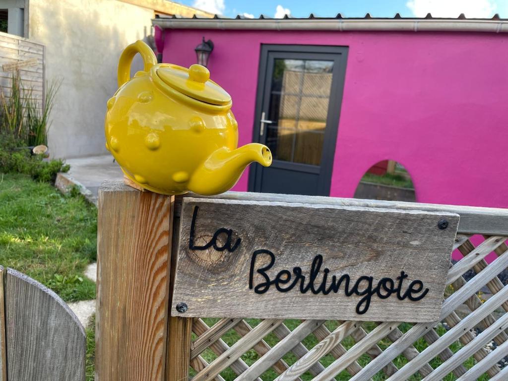 a yellow tea pot sitting on a sign on a fence at La Berlingote in Cherbourg en Cotentin
