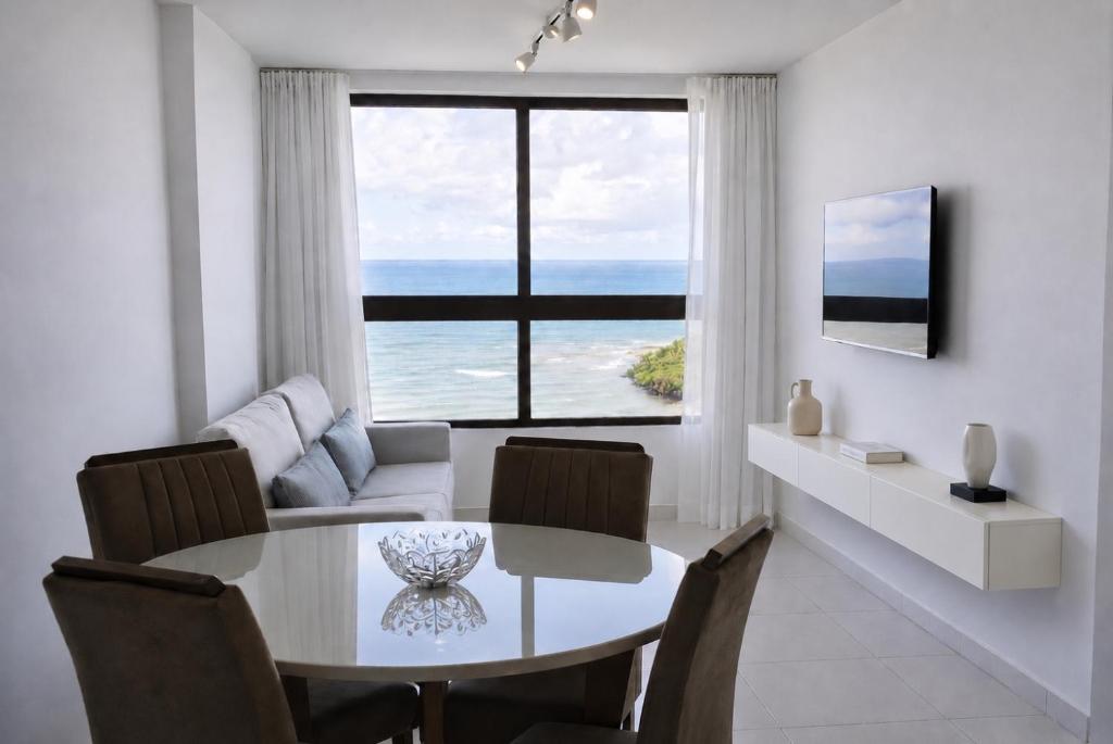 a living room with a dining table and a view of the ocean at Paiva Ocean View - 17th Floor with Pool, Sauna & Jacuzzi in Recife