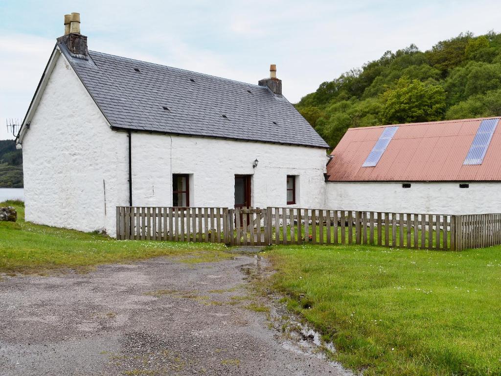 a white barn with a red roof and a fence at Port-An-Eillean in Feorlean