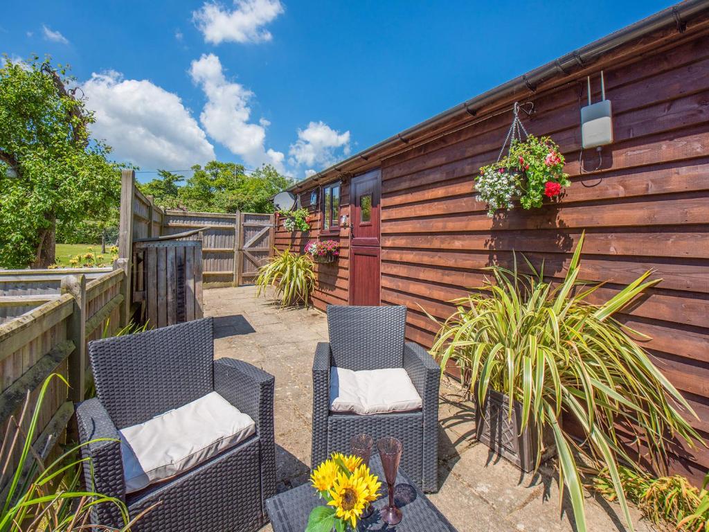 a patio with two chairs and flowers and a fence at The Lodge in Northiam