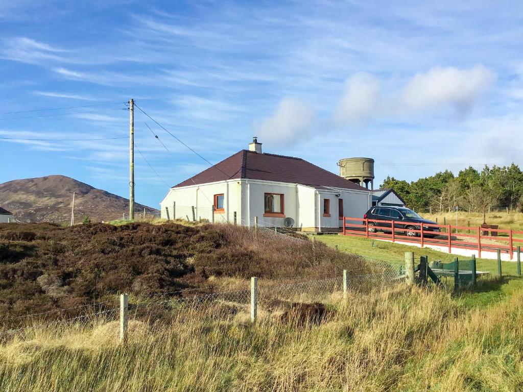 a small white house on a hill with a fence at Laxdale Cottage in Leverburgh