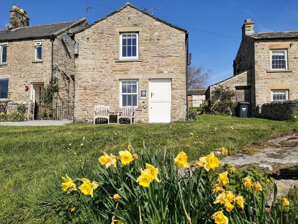 a stone house with yellow flowers in the yard at Lawson's Studio in Redmire