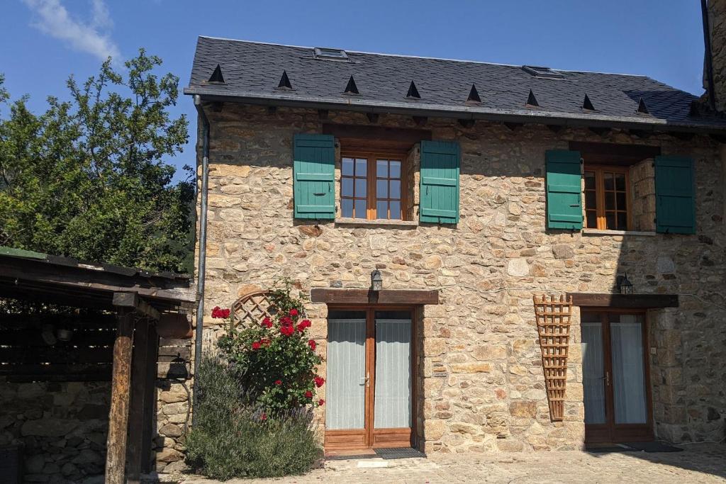 an old stone house with green shutters and flowers at La Grange de la Petite Ourse in Les Angles