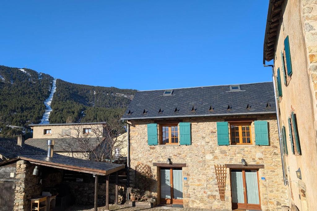 a stone building with a slate roof with a waterfall in the background at La Grange de Cassiopée in Les Angles