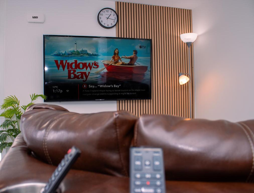 a flat screen tv hanging on a wall with a couch at Modern Private 2-Bedroom Styld, Spacious & Comfy-Modern New 2-Bedroom Stylish, Spacious, Comfy & Nicely Furnished - Full Privacy in St. John's