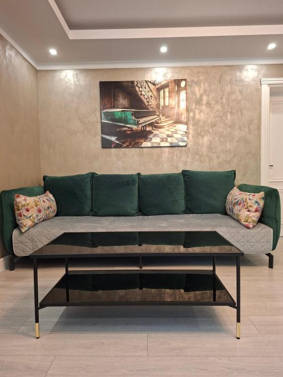 a green couch in a living room with a painting at ClausStudio Greenfield Baneasa Therme Aeroport in Otopenii de Jos