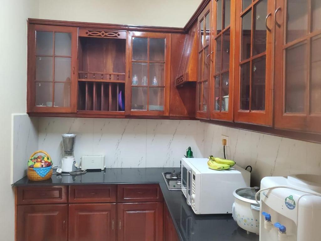 a kitchen with wooden cabinets and a microwave at Kalubowila Rooms in Dehiwala