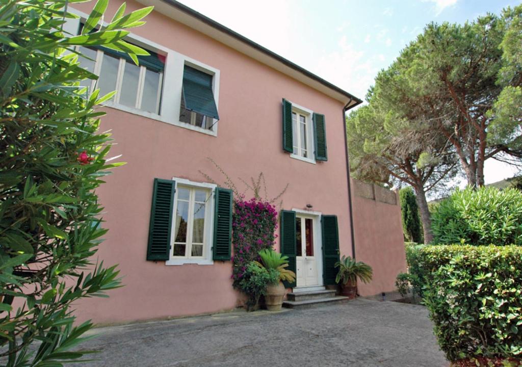 a pink house with green shutters and flowers at Villa Casa Rosa in Procchio