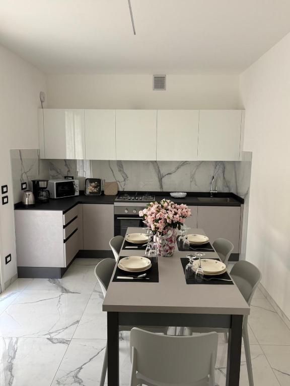 a kitchen with a table with chairs and flowers on it at Appartamenti Gemma in Calmasino