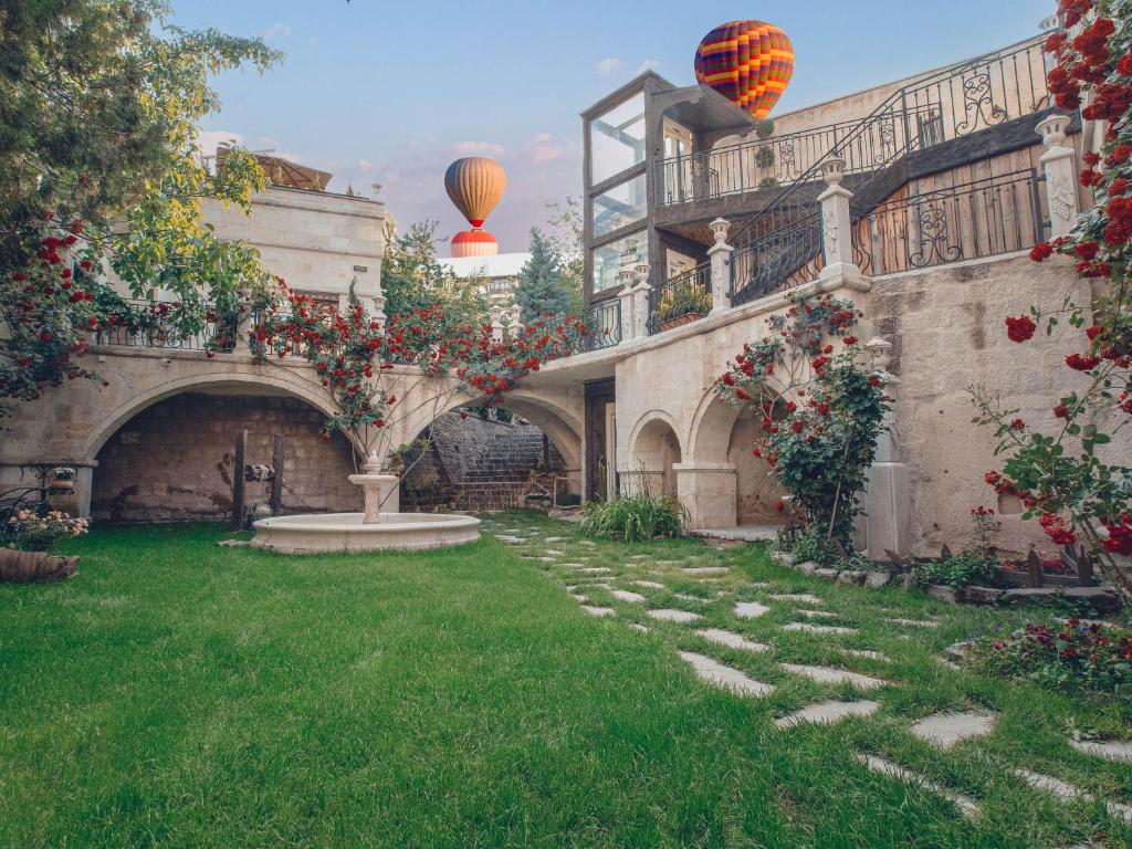 a garden with red flowers and two hot air balloons at Minia Cave Hotel in Ortahisar