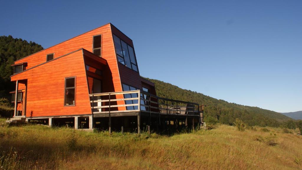 a wooden house on a hill in a field at Das Glashaus in Curacautín