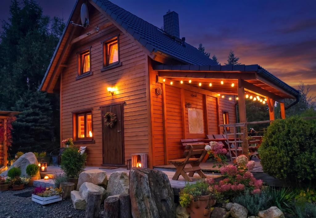 a log cabin with lights on the porch at night at Wierzbowy Jar- kameralny domek przy lesie w Rudawach Janowickich stworzony dla osób szukających spokoju in Janowice Wielkie