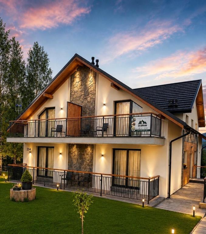a large white house with a balcony and a yard at Za Górami in Wetlina