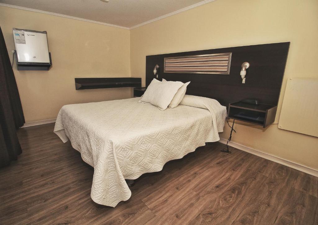a bedroom with a bed with a white comforter at Hotel Costa Marfil Baquedano in Antofagasta