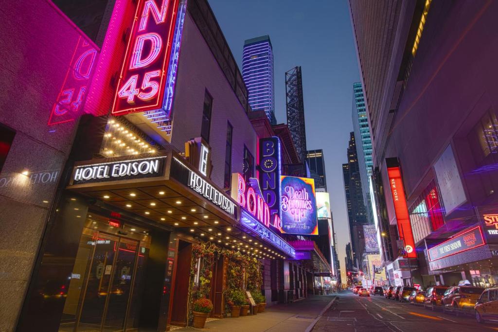 a city street at night with neon signs at Hotel Edison Times Square in New York