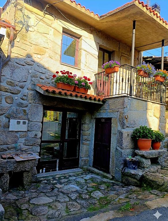 a stone house with potted plants on a balcony at Lobios House in Bubaces
