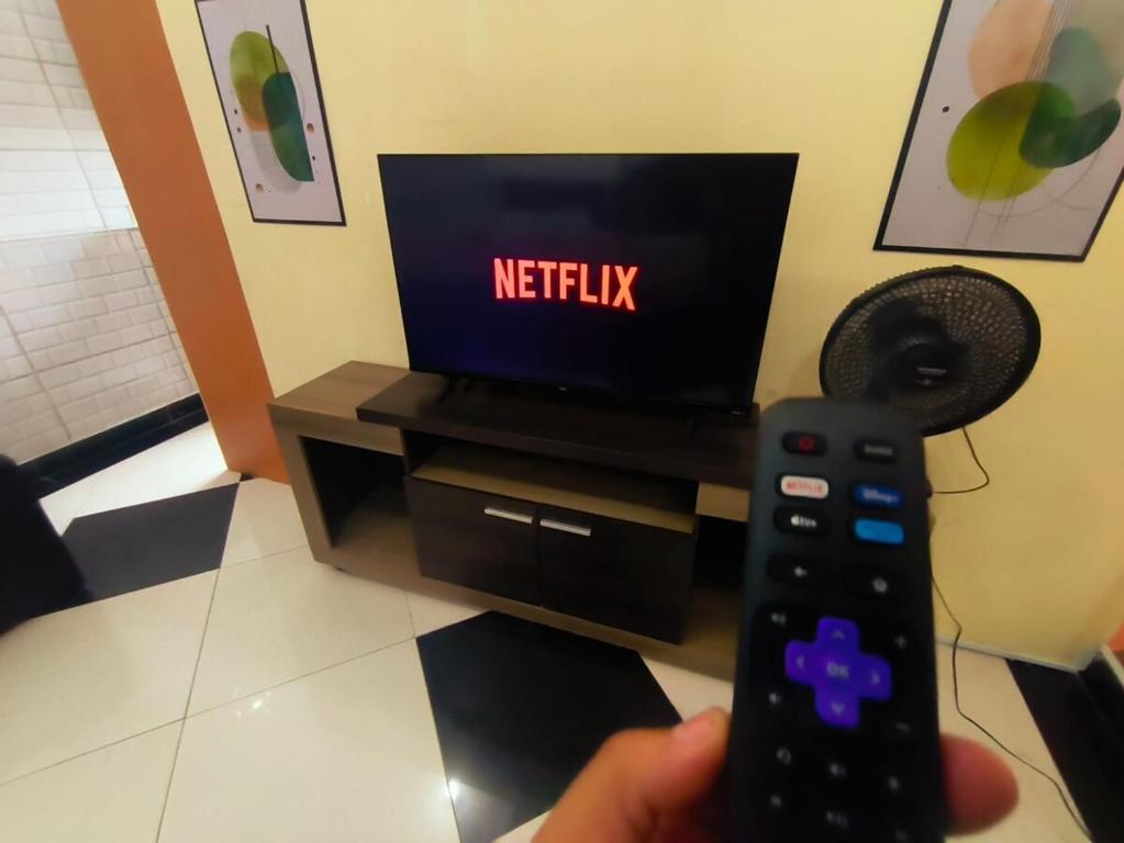 a person holding a remote control in front of a television at Diadema Studio - Apt 11 in Diadema