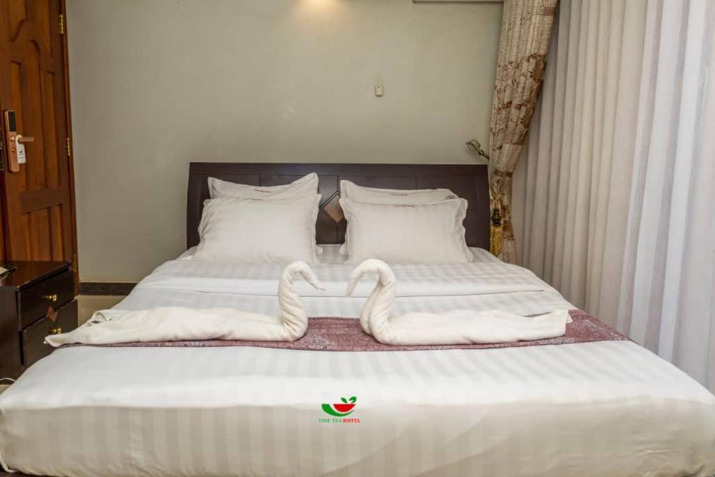 a bed with two swans made out of towels at Vinetea Hotel in Kampala