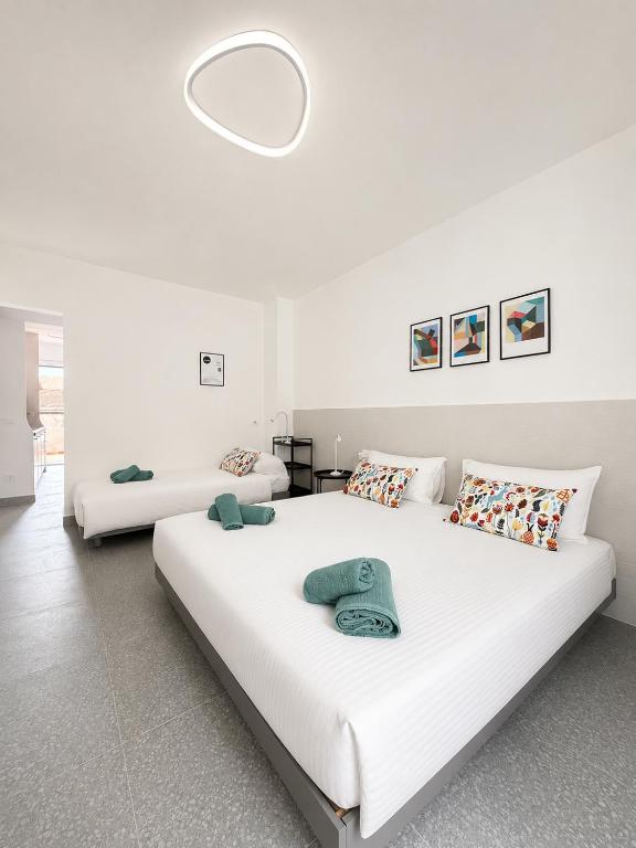 two beds in a room with white walls at Dietro le Quinte Rho Apartments in Rho