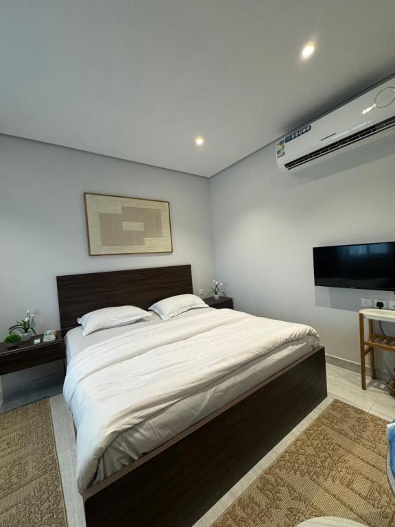 a bedroom with a large bed and a flat screen tv at Modren AD 23 in Dammam