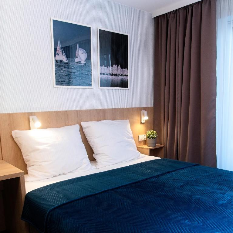 a hotel room with a bed with a blue blanket at Marina Apartamenty ChKŻ in Charzykowy