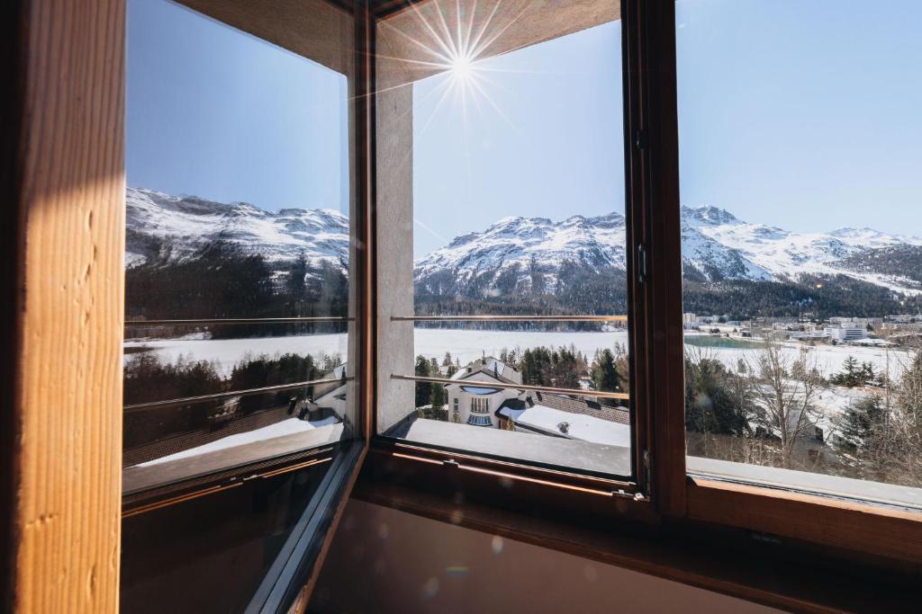 a window with a view of snow covered mountains at Villa Beaulieu in St. Moritz