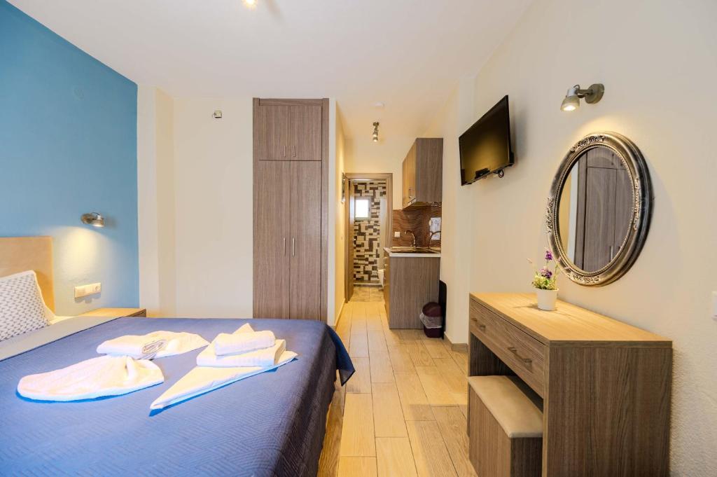 a bedroom with a blue bed and a mirror at Studios Sotiria 1 in Astris